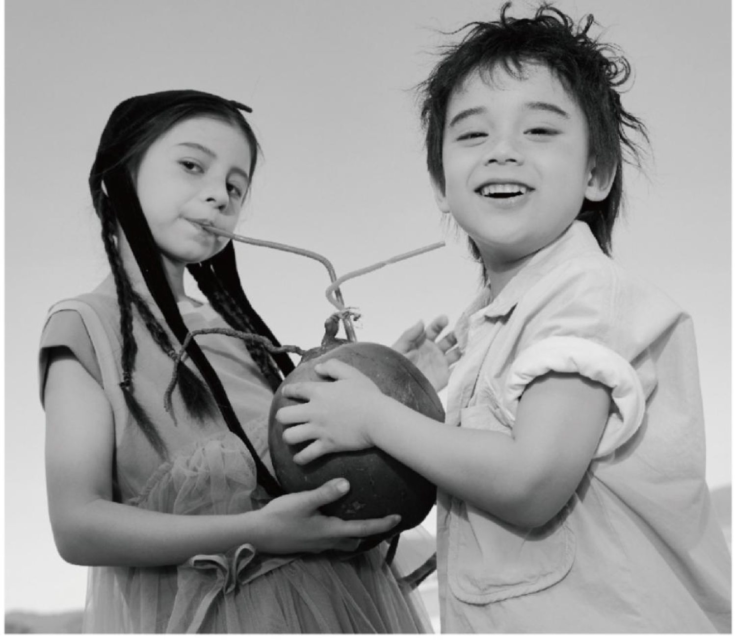 Two children sharing a fresh coconut, laughing together